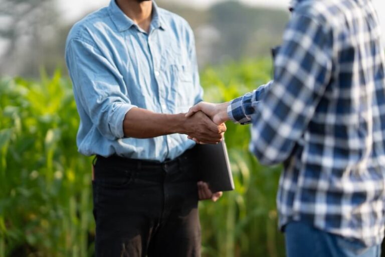 Farmer shaking hands with sales rep in crop field