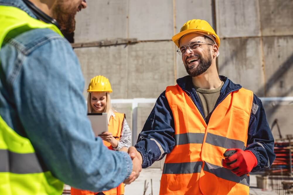 Two construction workers shaking hands after closing a deal.