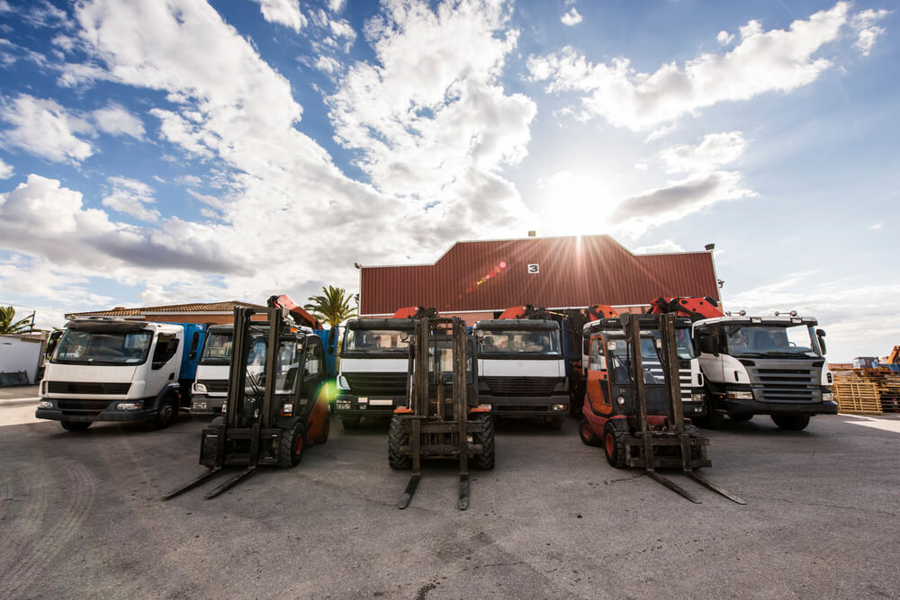 Lorries or trucks and forklift trucks parked at an industrial site.