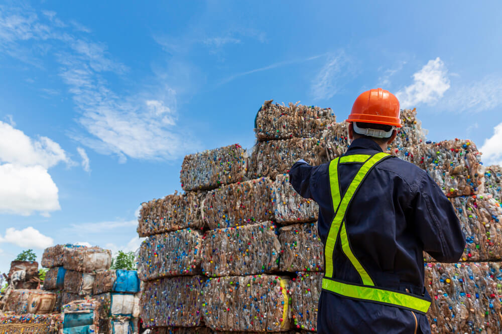 Piles of compacted recycled waste with an employee overseeing it.