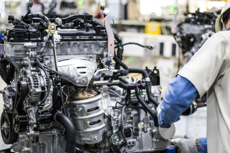 Worker assembling car engine in manufacturing production line. 