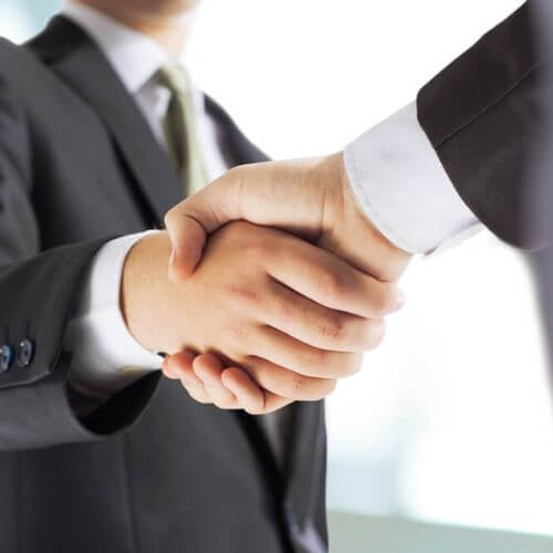 Two people in suits shaking hands.